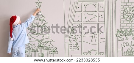 Little boy in Santa hat and pajamas decorating Christmas tree in drawn living room