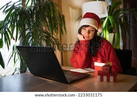 Serious thoughtful Santa woman sit at home desk with laptop thinking of inspiration solution for Christmas lost in thoughts dreaming looking away, search creative ideas concept
