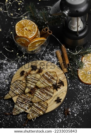 christmas decoration of dried pears in chocolate on a wooden stand of cinnamon oranges and Christmas tree branches of a lantern on a dark background. for postcards menu labels calendars signs and stan