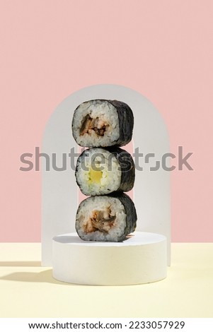 Asian culture, Japanese hosomaki (sushi, rolls) with eel on a pink and yellow background. Oriental culinary, eastern cooking. Tasty appetizers on platter