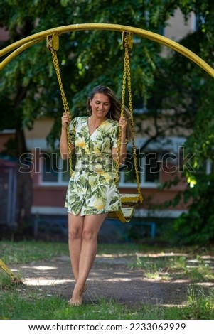 A woman with loose hair walks near her house and rides on a bright yellow swing