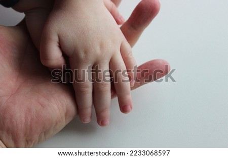 Small child's hand in the open palm hand of an adult human isolated stock photo 
