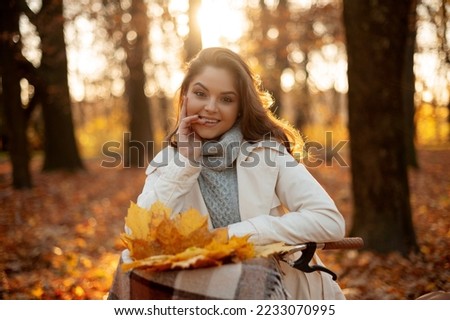 Portrait of the woman standing with bicycle and smiling to the camera in forest in autumn at sunset. Travel concept 