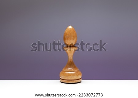 White Chess piece Bishop, officer or elephant. Old wooden Chessman for play the game of chess. Bishop on edge of table. Concept - loneliness.