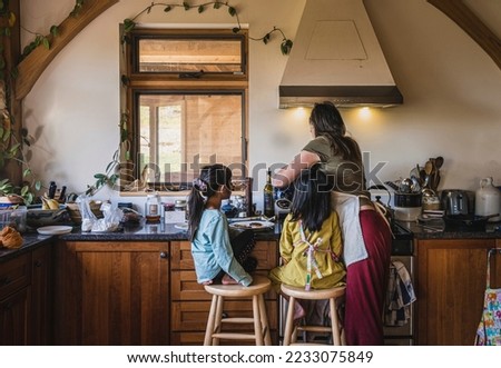 Mom making pancakes breakfast for two young adopted Indian daughters in kitchen Royalty-Free Stock Photo #2233075849