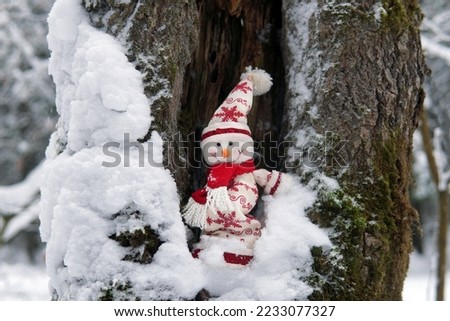 Christmas snowman toy in a hollow tree in winter
