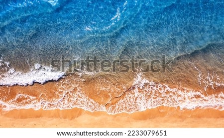 Turquoise water wave with sand beach background from aerial top view. Concept summer sunny travel image.