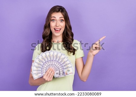 Photo of young worker lady wear t-shirt overjoyed hold much money after first extra salary finger direct mockup isolated on violet color background