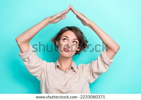 Photo of adorable lady arm make roof under head interested look empty space banner promo ad choice choose isolated on cyan color background