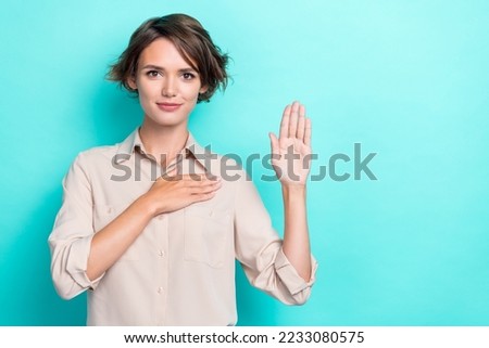 Photo of pretty lady calm face wear trendy outfit arm make symbol promise be devoted citizen empty space isolated on cyan color background