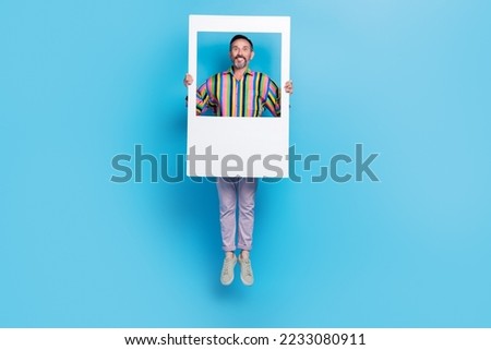 Full length photo of positive carefree man blogger hold picture frame dream million instagram followers isolated on blue color background