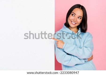 Photo of shiny dreamy girl dressed blue sweatshirt looking pointing blank board empty space isolated pink color background