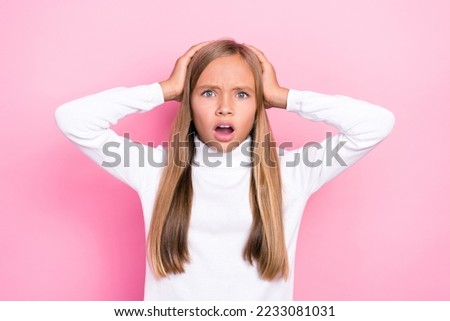 Portrait of impressed schoolchild hands touch head open mouth stare isolated on pink color background