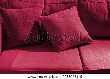 Multicolored pillow on sofa background. New 2023 trending PANTONE 18-1750 Viva Magenta color