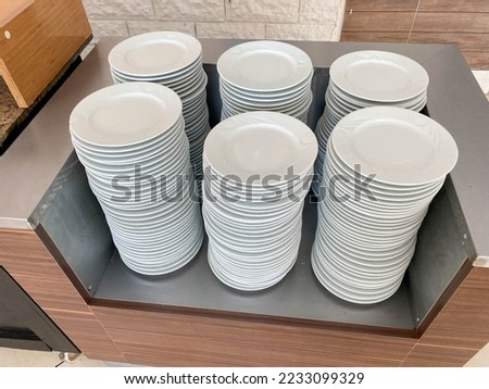 Many stacks of white ceramic plates clean washed in a cafe in the dining room in a cafe fast food restaurant.