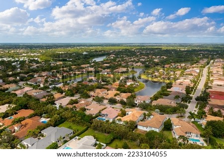 Aerial drone view to the suburbs in Delray Beach in Miami Florida, there is large tropical vegetation, houses with tiles and blue sky Royalty-Free Stock Photo #2233104055
