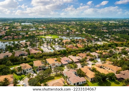Aerial drone view to the suburbs in Delray Beach in Miami Florida, there is large tropical vegetation, houses with tiles and blue sky Royalty-Free Stock Photo #2233104067