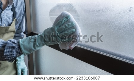 Condensation on windows in winter.Wipe with a dust cloth. Royalty-Free Stock Photo #2233106007