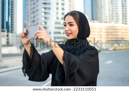 Young beautiful muslim middle eastern woman taking photo with mobile phone on the city street.