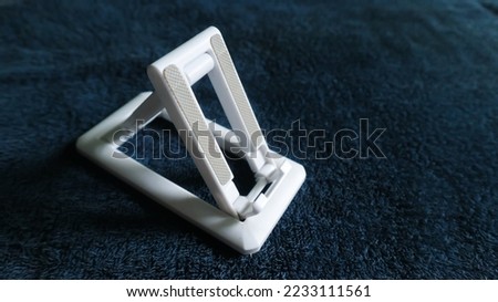 Photo of a white cellphone holder. functions as a balancer for mobile phones