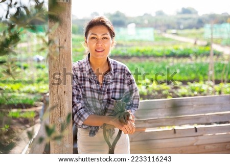 Portrait of kazah woman with gardening tools outdoors. Asian woman standing with shovel in her vegetables garden