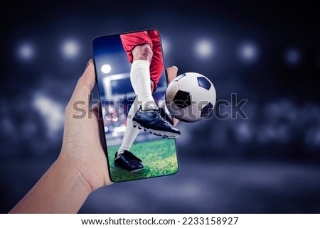 Close up of unknown man hand using a mobile phone to watching football match with blurred stadium background