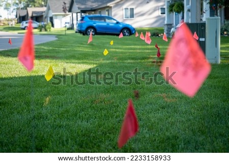 Warning flags on the green grass of a residential lawn, used to prevent injury when digging for landscaping. Royalty-Free Stock Photo #2233158933