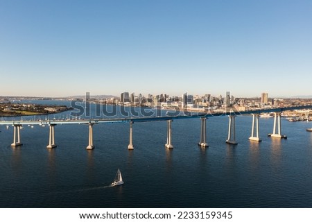 Coronado bridge with San Diego skyline in distance, sail boat in foreground. 