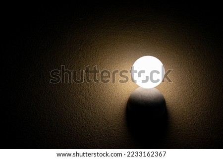 Round neon light on light yellow color in the dark room background.