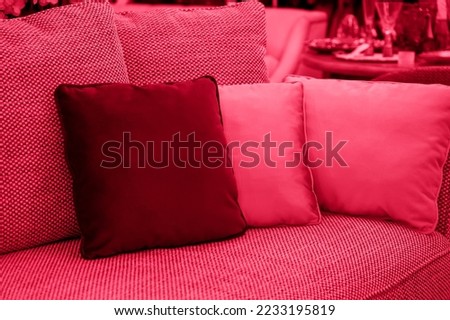 Image toned in pantone color of year 2023 viva magenta. cushions on cozy red sofa. Pillows on casual couch in the living room