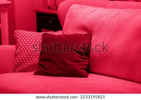 Image toned in pantone color of year 2023 viva magenta. cushions on cozy red sofa. Pillows on casual couch in the living room Royalty-Free Stock Photo #2233195821