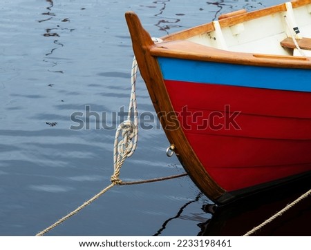 Clinker built boat painted red and blue and tied up with one of many nautical knots.