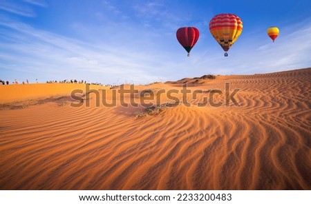 Hot air balloons flying over beautiful sand dunes sunset in the Mui Ne Red Sand Dunes in the North of Mui Ne Village, about 25 km from Phan Thiet City, Vietnam Royalty-Free Stock Photo #2233200483