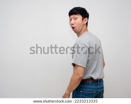Asian young man grey shirt feels amazed turn back to looking isolated Royalty-Free Stock Photo #2233213335