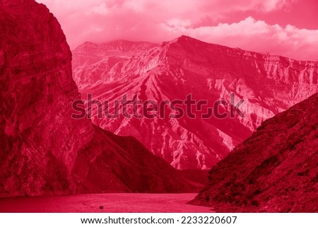 Motor boat on scenic river among rocks and mountains. Image toned in pantone color of year 2023 Viva Magenta. Confluence of Avar koysu and Andi koysu into Sulak river.