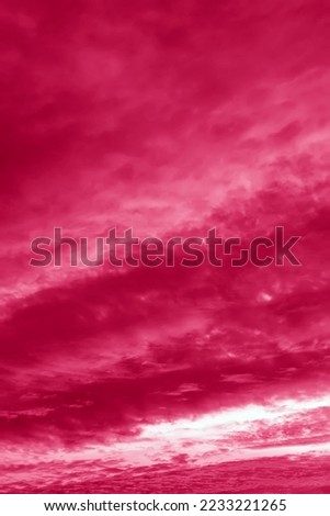 Image toned in pantone color of year 2023 viva magenta. Pink sunset sky clouds with majestic orange sunlight twilight in evening, majestic ​sky vertical.