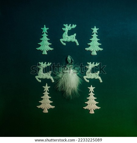Christmas decorative ornaments, ballerina in a lovely white costume, ceramic reindeer figurines and Christmas trees on a blue green background. Flat lay concept.