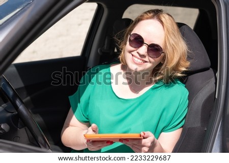 Happy smiling girl using application on digital tablet in a car. Happy girl student, working remotely, reading social media internet, typing text. Distance learning, online education and work