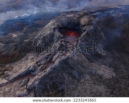 dark volcanic landscape in Iceland. Volcanic crater from above before eruption on Reykjanes Peninsula. View of the red lava structures in the crater's mouth and smoke around the crater.