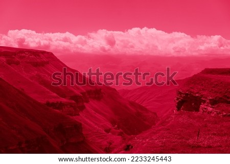 Beautiful sunny day in mountain valley and mountainous countryside landscape in summer. Image toned in pantone color of year 2023 Viva Magenta. Mountain range under cloud blue sky.