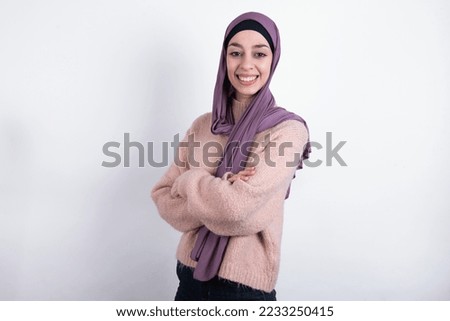 muslim woman wearing hijab and knitted sweater over white background happy face smiling with crossed arms looking at the camera. Positive person.