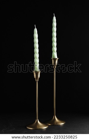 Vintage metal candlesticks with candles on table against black background Royalty-Free Stock Photo #2233250825
