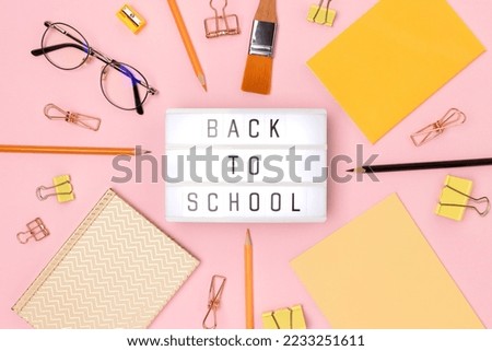 Back to school. Lightbox with letters and frame made of stationery on a pink background.