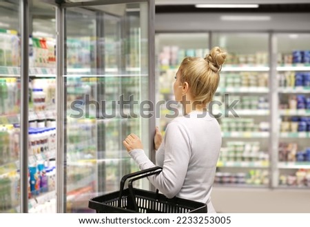 Woman choosing frozen food from a supermarket freezer Royalty-Free Stock Photo #2233253005