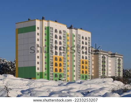 Modern architecture. New multi-storey and multi-apartment residential building. Neighborhood on the outskirts of the city. Winter, snow and pines Royalty-Free Stock Photo #2233253207