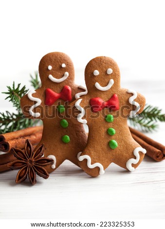 Smiling gingerbread men on white wooden background
