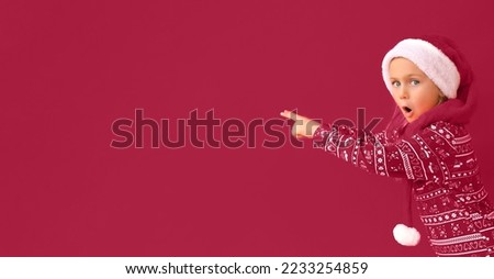 Excited surprise kid girl wearing Christmas Santa hat isolated pantone color 2023 viva magenta studio background with finger pointed up. sale and discount. Shopping. Banner copy space