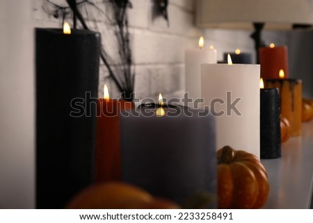 Burning candles and different Halloween decor indoors