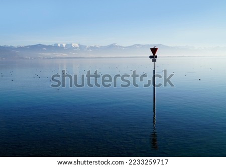 empty harbour of Lindau island on tranquil lake Constance or lake Bodensee with the Austrian Alps in the background on a fine winter evening with blue sky reflected in the water (Germany)              Royalty-Free Stock Photo #2233259717