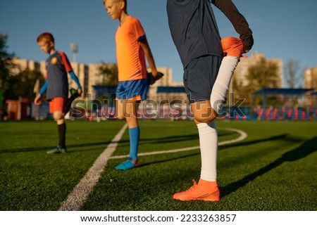 Young boys football players doing warm up workout stretching legs Royalty-Free Stock Photo #2233263857